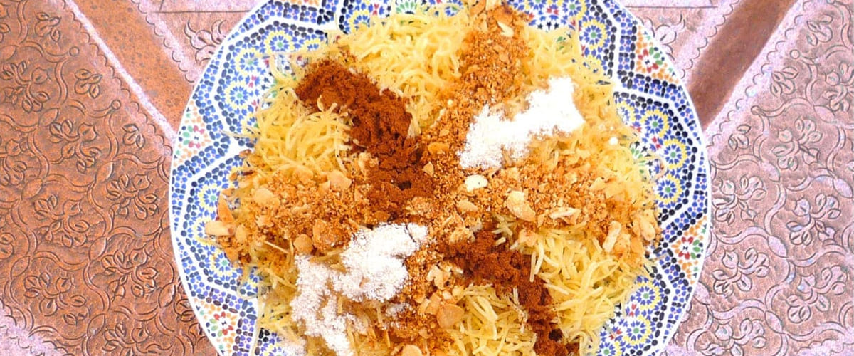 Recipe to make Moroccan Pasta with Almonds, Cinnamon & Culinary Argan Oil photo of plate of moroccan seffa pasta crossed with powdered cinnamon, sugar, almonds of 1 meter wide engraved copper moroccan plate